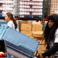 Two students loading food into plastic tubs